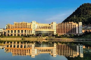 Un hotel grande con varios pisos, un patio central y un reflejo en el agua.