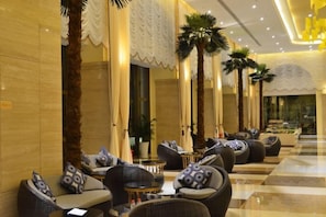 A hotel lobby with seating areas, palm trees, and a check-in desk. - Island International Hotel (Liupanshui)