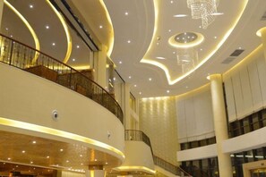 A multi-level interior with curved architectural lines, a central staircase, and a chandelier. - Island International Hotel (Liupanshui)
