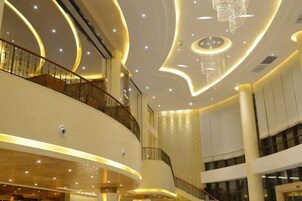 Un interior de varios niveles con líneas arquitectónicas curvas, una escalera central y una araña.
