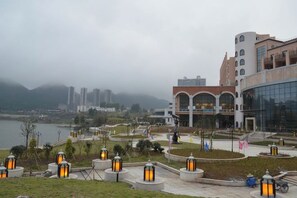 A waterfront promenade with modern buildings, a river, and outdoor lighting fixtures. - Island International Hotel (Liupanshui)