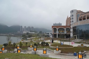 Un paseo marítimo con edificios modernos, un río y faroles.