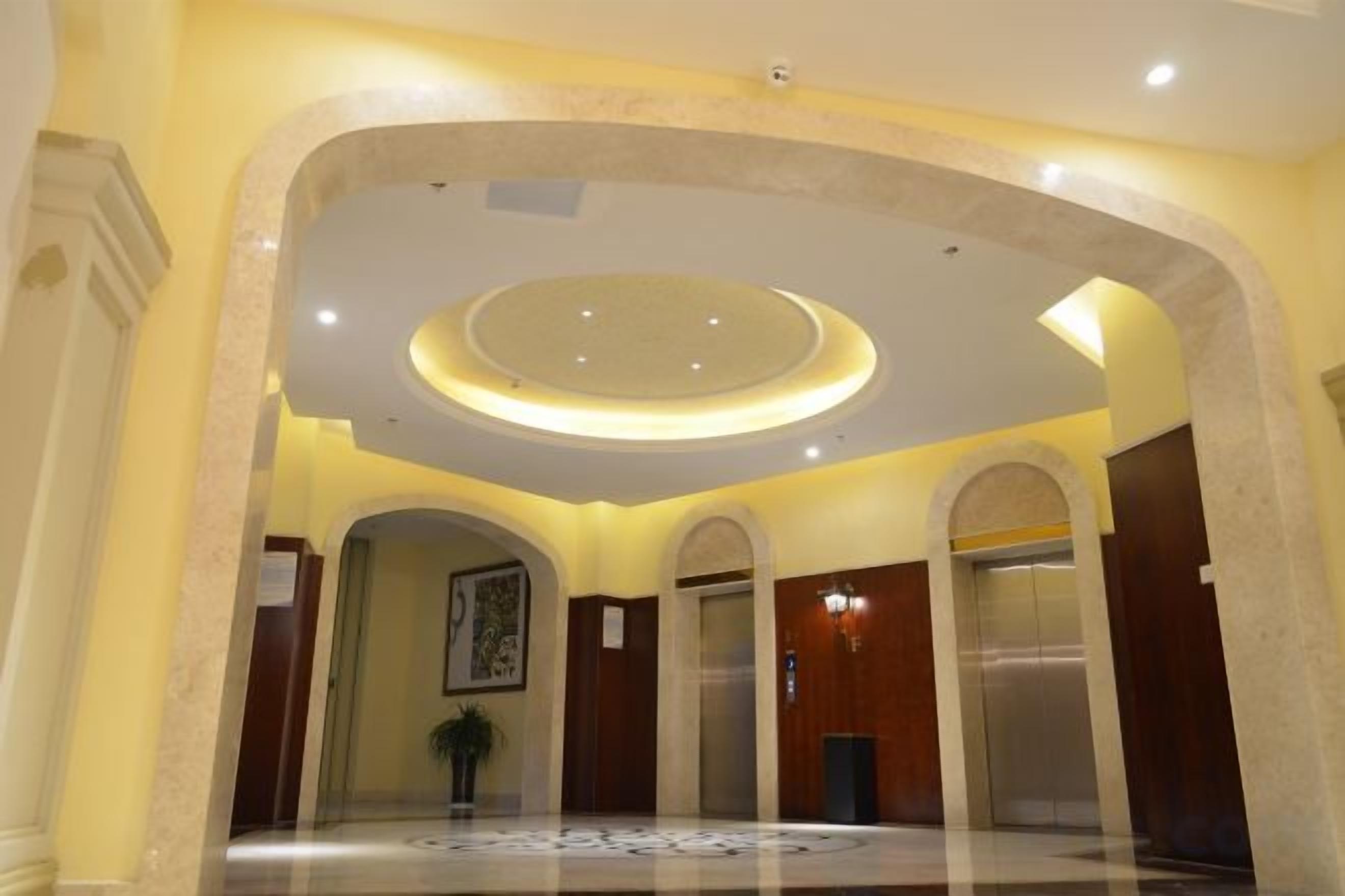 A hotel lobby with a circular ceiling design, marble flooring, and wooden doors.