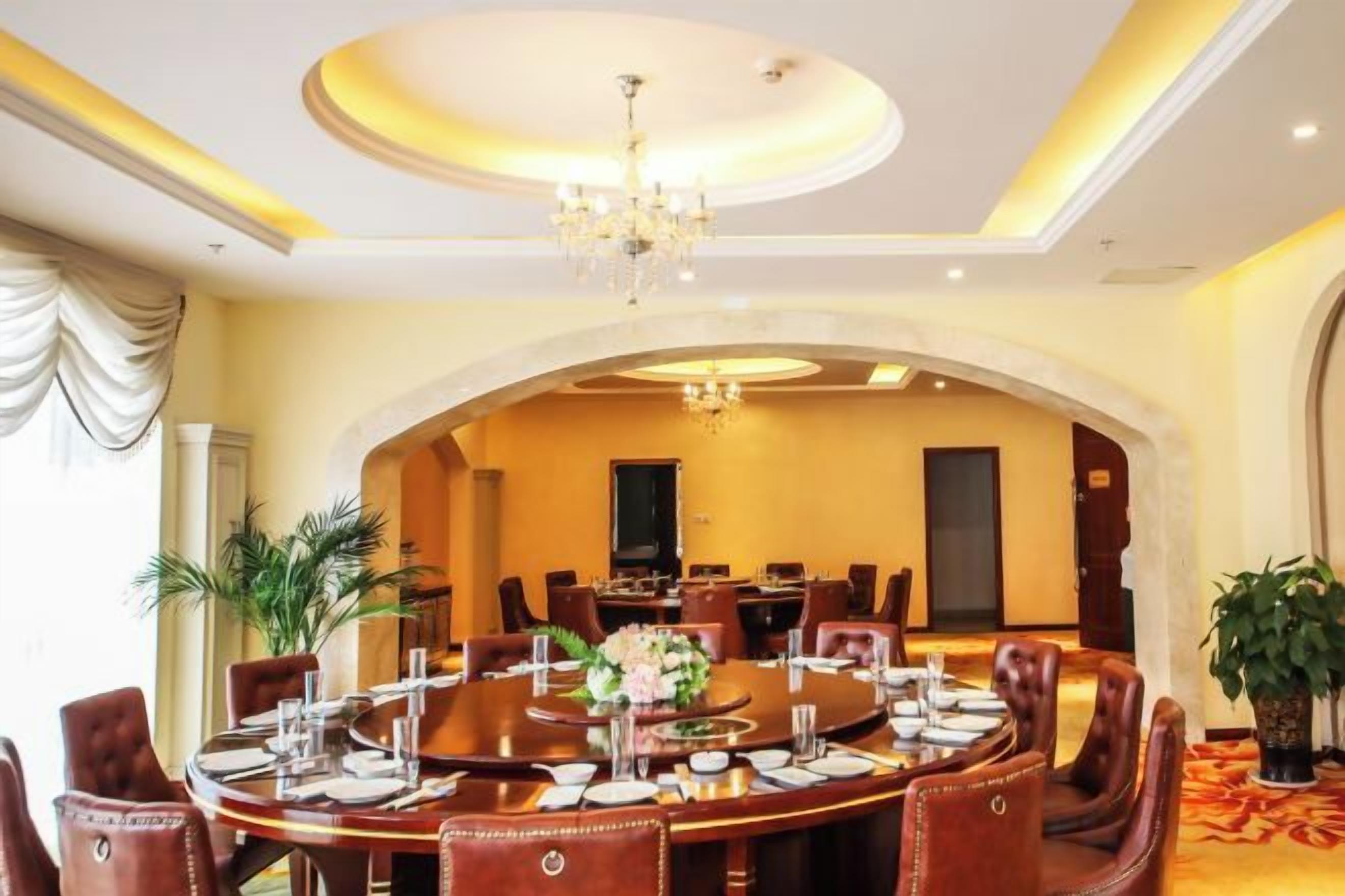 A formal dining room with a round table, chairs, and a chandelier.