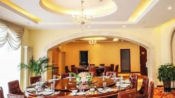 A formal dining room with a round table, chairs, and a chandelier.