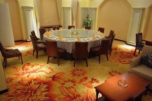 A round dining table with chairs, a sofa, and a small table with a glass object.