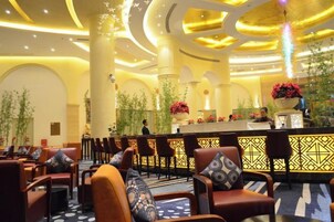 Un hall de hotel con mostrador de recepción, zona de estar y plantas decorativas.