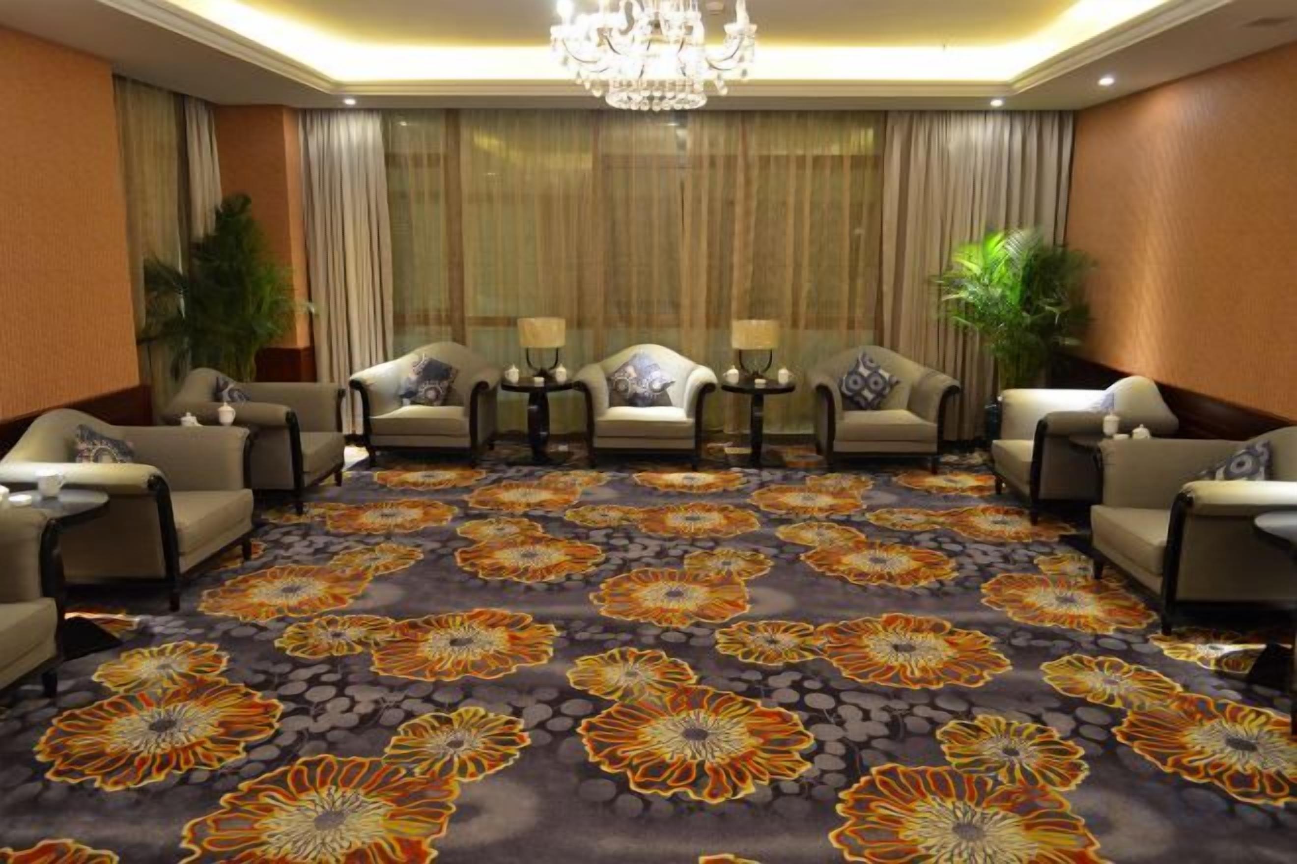 A hotel room with a large floral carpet, multiple sofas, and a chandelier.