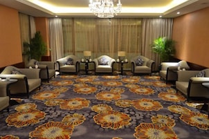 Habitación de hotel con una alfombra floral grande, varios sofás y una araña.