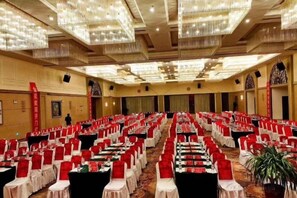 A conference room with rows of tables and chairs, large chandeliers, and a carpeted floor. - Island International Hotel (Liupanshui)