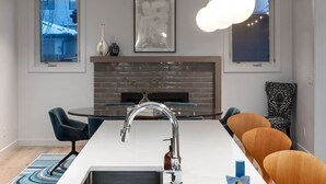Une cuisine moderne dotée d’un îlot central, d’un évier encastré et d’un luminaire suspendu.