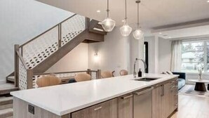 Une cuisine moderne dotée d’un îlot central, de meubles en bois et de luminaires suspendus.