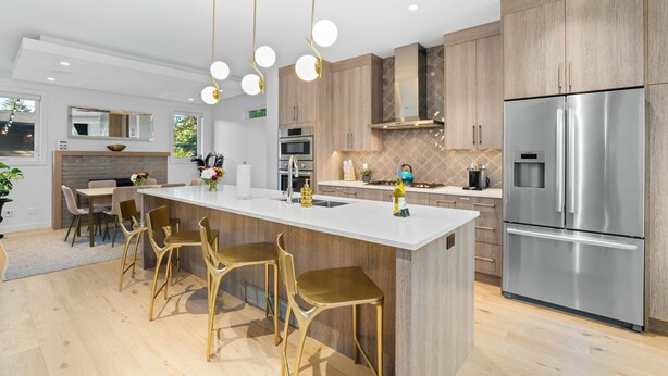 Une cuisine moderne dotée d’un îlot central, d’appareils électroménagers en acier inoxydable et de meubles de rangement en bois.