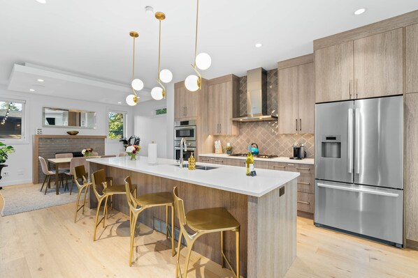 A modern kitchen with a central island, stainless steel appliances, and wooden cabinetry.