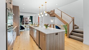 Une cuisine moderne avec des meubles en bois, un îlot central et des luminaires suspendus.