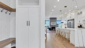 Una cucina moderna con mobili bianchi, sgabelli da bar in legno e illuminazione a sospensione.