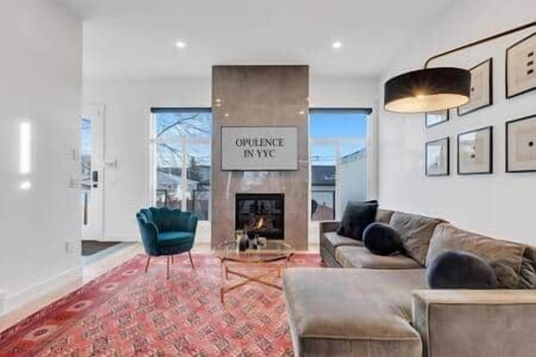 A modern living room with a fireplace, a blue armchair, a beige sofa, and a red patterned rug.