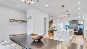 Una cucina moderna con isola centrale, mobili bianchi e una ciotola di legno sul piano di lavoro.