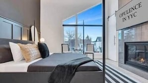 Camera da letto moderna con un letto grande, un camino e vista sull'esterno.