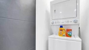 A white washing machine with detergent bottles on top. - The Olaf in Trendy Killarney - Close to Everything (Calgary)