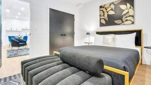 A modern bedroom with a bed, a chair, and a painting on the wall. - The Olaf in Trendy Killarney - Close to Everything (Calgary)