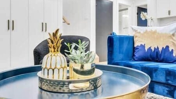 A modern living room with a blue sofa, a coffee table with decorative items, and white cabinets. - The Olaf in Trendy Killarney - Close to Everything (Calgary)