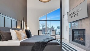 Une chambre moderne avec un grand lit, une cheminée et une vue sur l’extérieur.