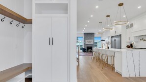 Une cuisine moderne avec des meubles blancs, un îlot en marbre et des luminaires suspendus.