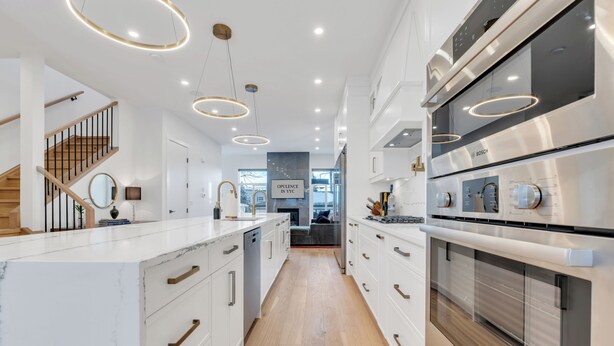 Une cuisine moderne avec des meubles blancs, un four Bosch et un escalier en bois.