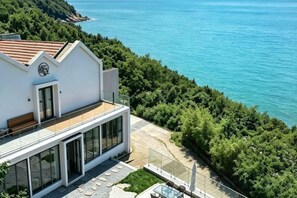 A modern house with a balcony overlooking a coastal area.