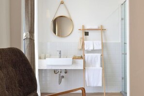 A bathroom with a white sink, a round mirror, a towel rack, and a shower area. - Qingdao Qigu Abalone Island No.85 Homestay (Qingdao)