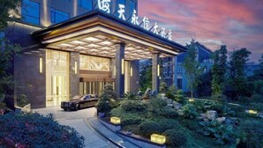 A modern hotel entrance with a covered walkway, large windows, and a landscaped garden area. - Haitian Yongxin Hotel (Qionglai)