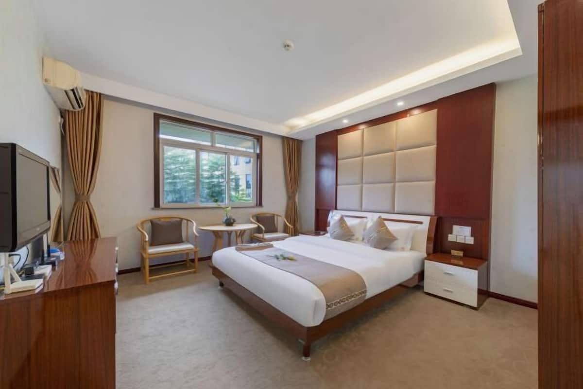 Hotelkamer met een groot bed, een bureau, een stoel, een televisie en een raam met gordijnen.