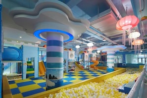 An indoor play area with a checkered floor, colorful play structures, and a ball pit.