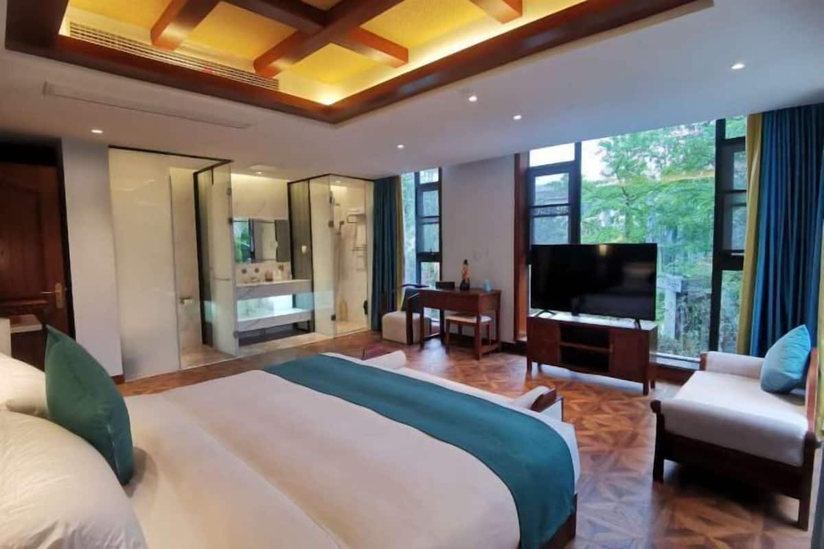 Een hotelkamer met een groot bed, een bureau met stoel, een televisie en uitzicht op de omgeving.