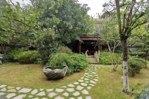 A garden with a stone pathway, a wooden pergola, and various plants. - Haitian Yongxin Hotel (Qionglai)