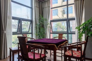 Una habitación con una mesa y sillas, ventanas amplias y vistas a edificios.
