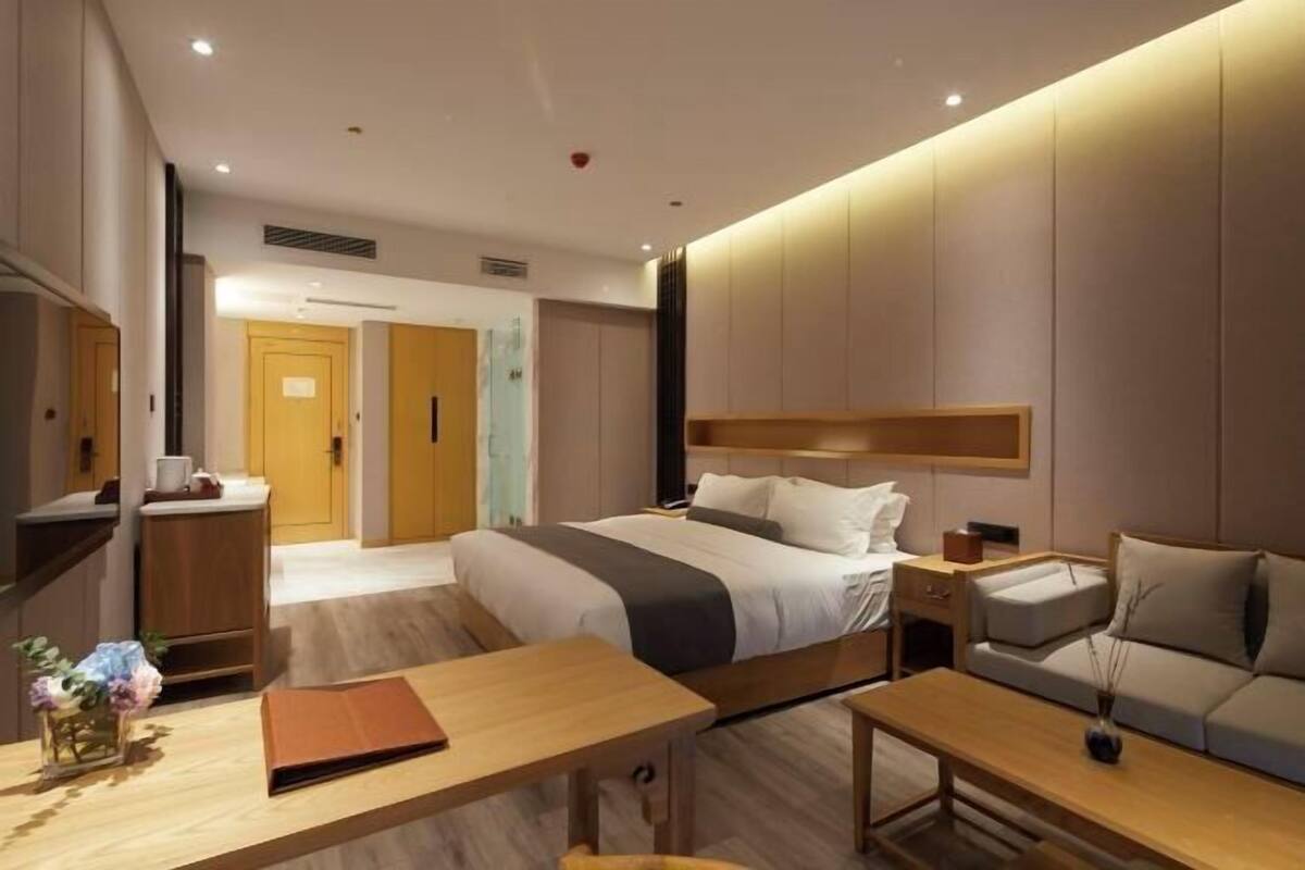 Een moderne hotelkamer met een bed, nachtkastje, bureau, bank en een kleine tafel met een vaas.