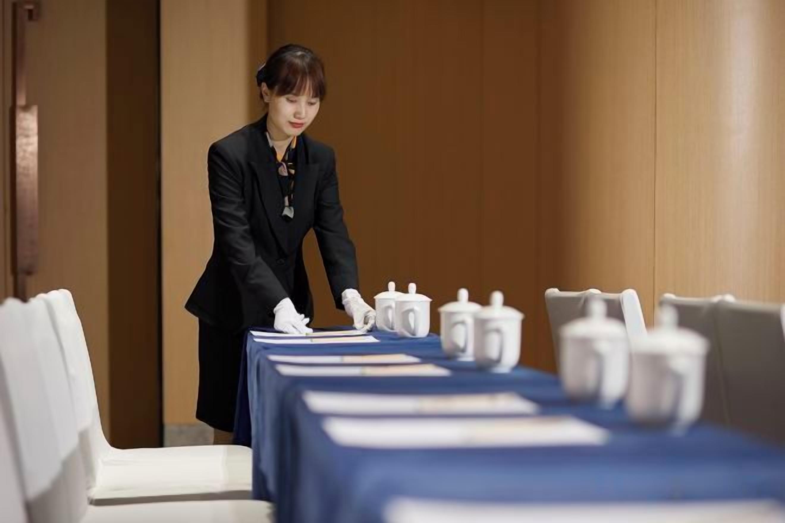 Une chambre d’hôtel avec une table à manger soigneusement dressée, agrémentée de vaisselle blanche.