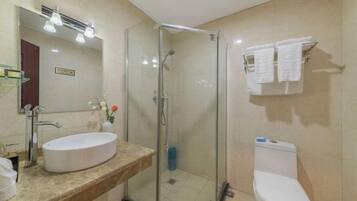 A bathroom with a glass-enclosed shower, a white sink, and a toilet.