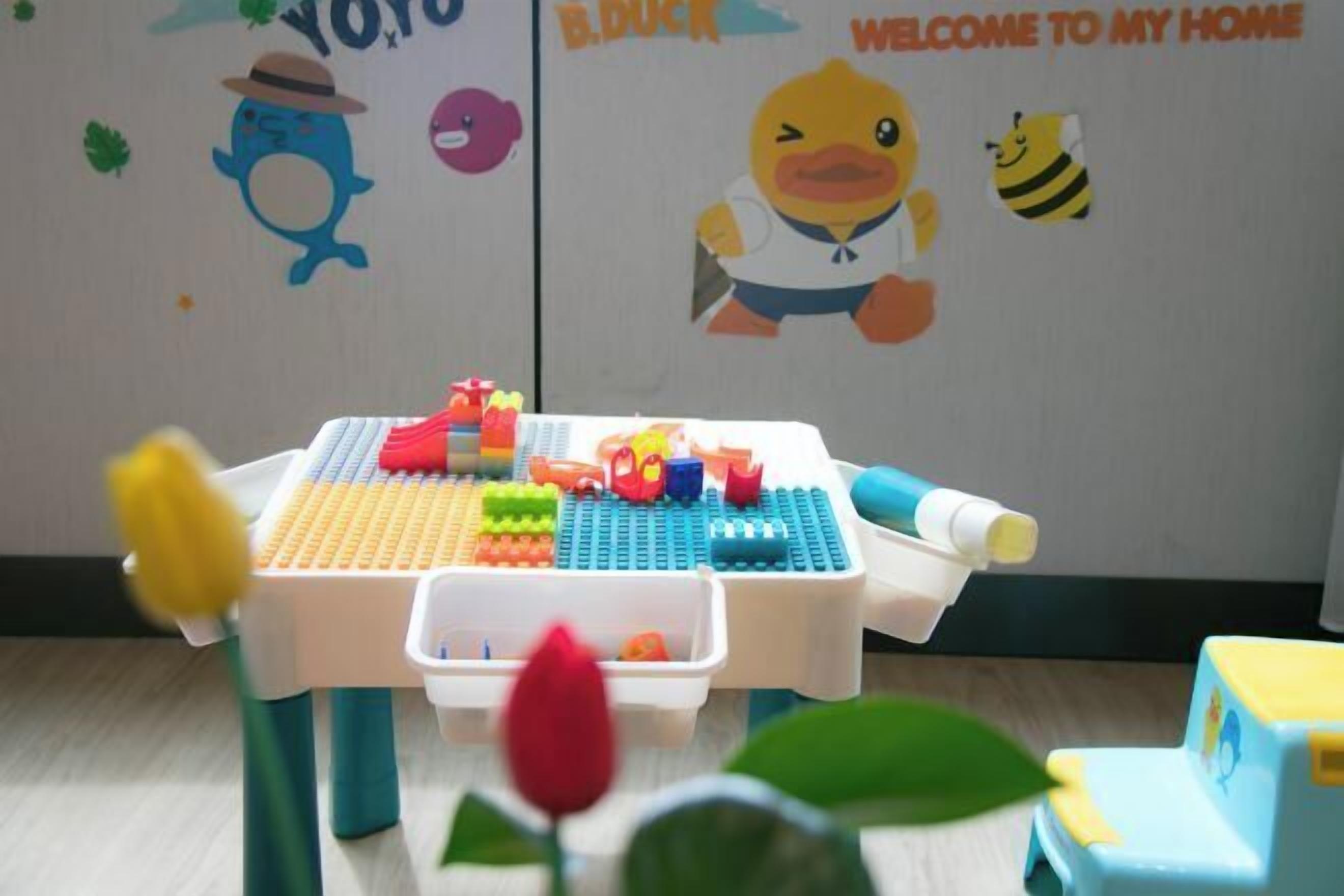 A child's play area with a table, toys, and a wall with cartoon characters.