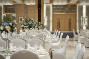 A banquet hall with round tables set for a formal event, featuring white chairs and floral centerpieces. - Haitian Yongxin Hotel (Qionglai)