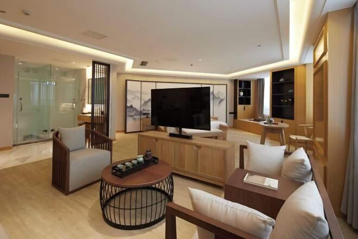Een moderne woonkamer met een flatscreen televisie, comfortabele zithoek, een salontafel en een glazen scheidingswand.