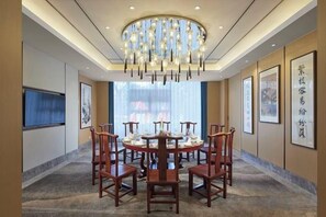 A conference room with a round table, chairs, a chandelier, framed artwork, and a large window. - Haitian Yongxin Hotel (Qionglai)