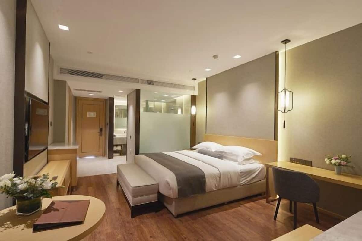 Een hotelkamer met een bed, nachtkastje, stoel en bureau met lamp.