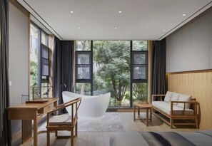 Ein modernes Schlafzimmer mit großem Fenster, einer Badewanne, einem Sofa und einem Schreibtisch.
