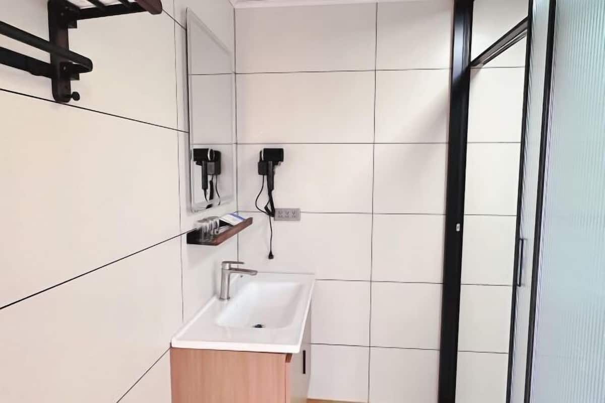 Un baño con un lavabo blanco, tocador de madera y un espejo.