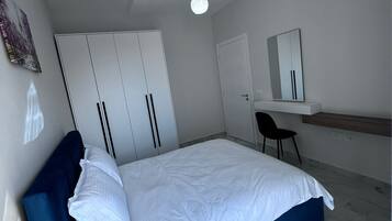 Ett modernt sovrum med en säng, en garderob, ett skrivbord och en stol.