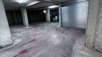 Un estacionamiento en construcción con pilares de hormigón, una puerta de garaje cerrada y un coche dentro.