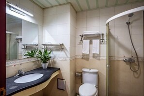 A bathroom with a sink, toilet, shower, and a mirror. - Yageba Hotel (Lijiang)